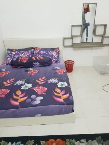 a bed with a purple blanket with flowers on it at Alfateh MU5L1M Homestay in Sungai Petani