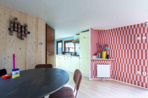 a dining room with a table and a kitchen at Kleurrijk boshuisje Sole op de Veluwe in Putten