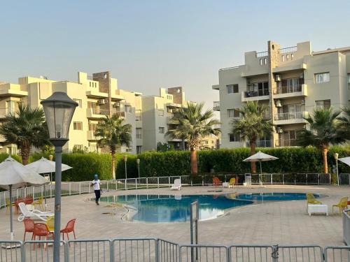 a person walking by a swimming pool in front of some buildings at Modern apartment with garden in Sheikh Zayed