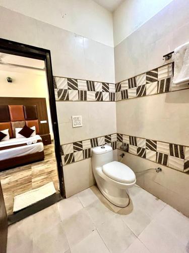 a bathroom with a toilet and a bed at Hotel WoodCrest Chandigarh Zirakpur in Chandīgarh