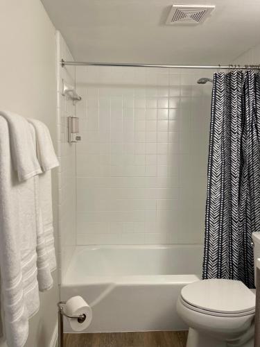 a white bathroom with a tub and a toilet at Shortest Walk to Shands and UF Health - Quiet, Equipped, Reliable - Free Parking in Gainesville