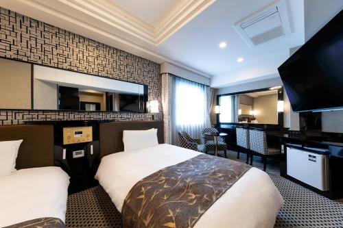 a hotel room with two beds and a flat screen tv at APA Hotel Nishifunabashi Ekimae in Funabashi