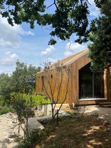 ein holzverkleidetes Haus mit einem großen Fenster in der Unterkunft Le Cigalou in Valaurie
