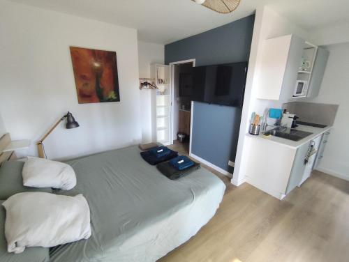 une petite chambre avec un lit et une cuisine dans l'établissement Studio with garden and pool, easy Nîmes access, à Caissargues