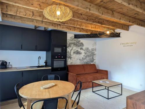 eine Küche und ein Wohnzimmer mit einem Tisch und einer Couch in der Unterkunft Escale Lomy en bord de mer avec Sauna et Jacuzzi in Pléneuf-Val-André