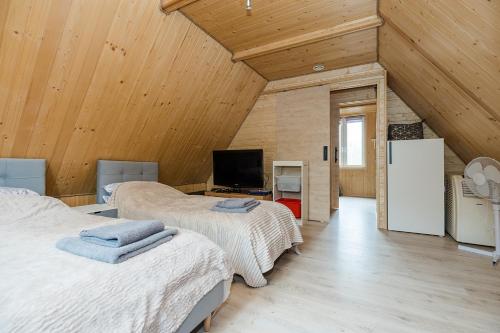 two beds in a room with wooden ceilings at Całoroczny, drewniany domek przy lesie in Prażmów