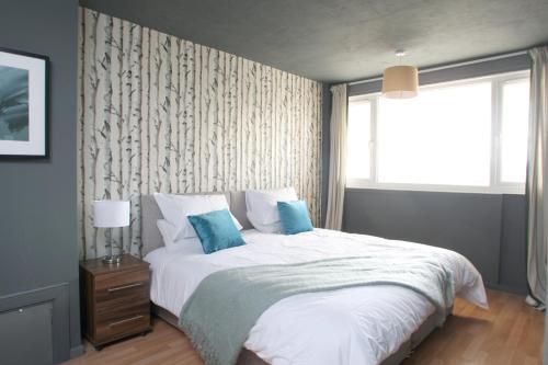 a bedroom with a bed with blue pillows and a window at Southside Apartment Glasgow in Glasgow