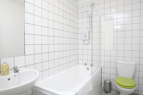 a bathroom with a tub and a toilet and a sink at Southside Apartment Glasgow in Glasgow