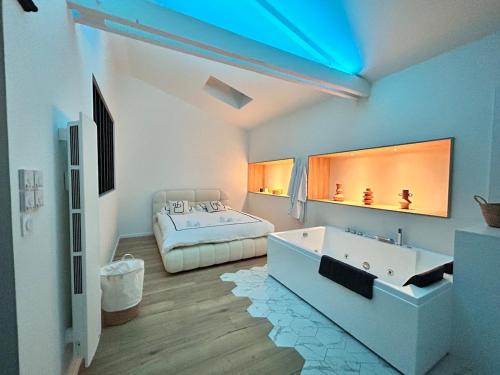 a bedroom with a bed and a tub and a sink at Un toit pour 2 in Le May-sur-Èvre