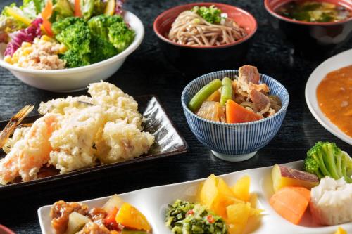 una mesa cubierta con cuencos de diferentes tipos de alimentos en Hotel Vista Kumamoto Airport, en Ozu