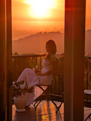 a woman sitting in a chair watching the sunset at Mada Nature in Mount Tamborine