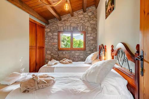ein Schlafzimmer mit zwei weißen Betten und einem Fenster in der Unterkunft El Vilarot. La casa de piedra en la naturaleza. in Girona