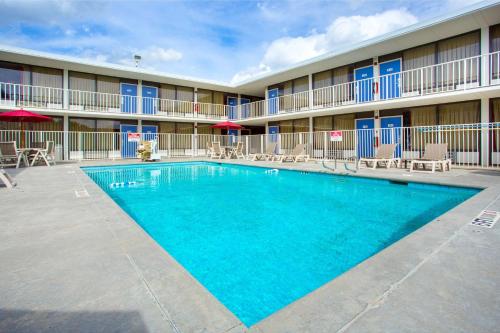 a pool in front of a hotel with tables and chairs at Motel 6 Baton Rouge Southeast in Baton Rouge