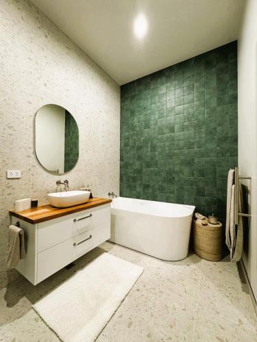 a bathroom with a tub and a sink and a mirror at Mylan on Marine - Historic Charm, Modern Heart in Burnie