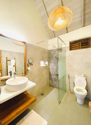 a bathroom with a sink and a toilet and a glass shower at Oruwa Boutique Villa in Pottuvil
