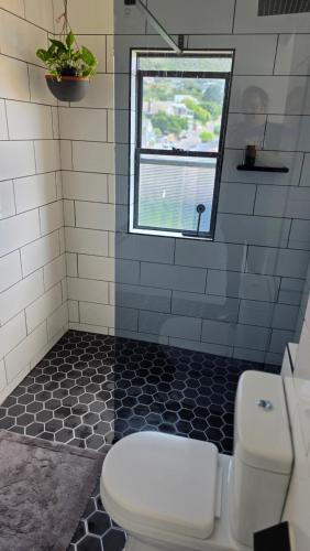a bathroom with a toilet and a window at Modern Sea and Mountain View Apartment - Gordon's Bay in Gordonʼs Bay