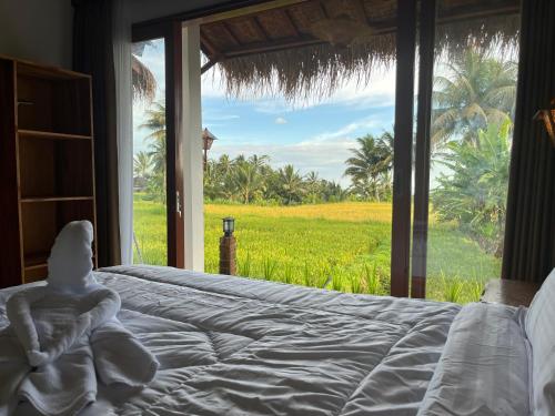 a bedroom with a bed and a view of a field at Rice Terrace Bungalows in Tetebatu