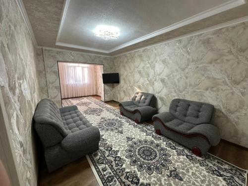ein Wohnzimmer mit zwei Stühlen und einem Fernseher in der Unterkunft Апартаменты рядом с центром in Qoraqamish