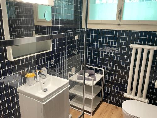 La salle de bains est pourvue de carrelage bleu, de toilettes et d'un lavabo. dans l'établissement Casa Colombina & Studio by Fewotessin, à Gordola