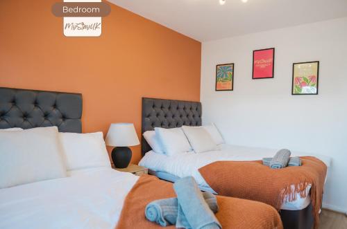 a bedroom with two beds and an orange wall at 3BR House By MyStayUK Short Lets & Serviced Accommodation Manchester With Free Wifi & Free Parking in Manchester
