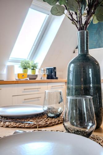 a table with a vase and two glasses on it at Cocon - Sélestat - Parking gratuit - Proche Europa-Park - Route des Vins - Haut-Koenigsbourg in Sélestat