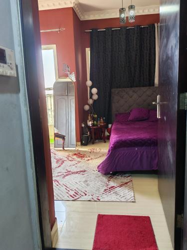 ein Schlafzimmer mit einem lila Bett und roten Wänden in der Unterkunft استديو لشخصين in Ajman 