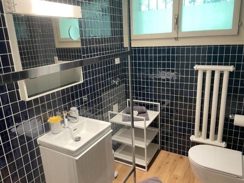 a blue tiled bathroom with a toilet and a sink at Casa Colombina Duplex by Fewotessin in Gordola