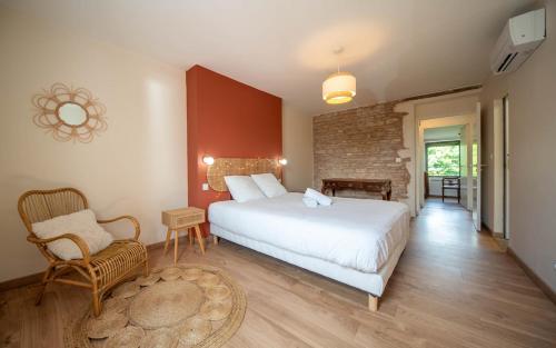 a bedroom with a large white bed and a chair at La Cave des Miracles in Dracy-le-Fort