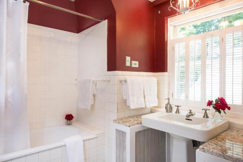 a white bathroom with a sink and a tub and a window at Inn on Putney Road in Brattleboro
