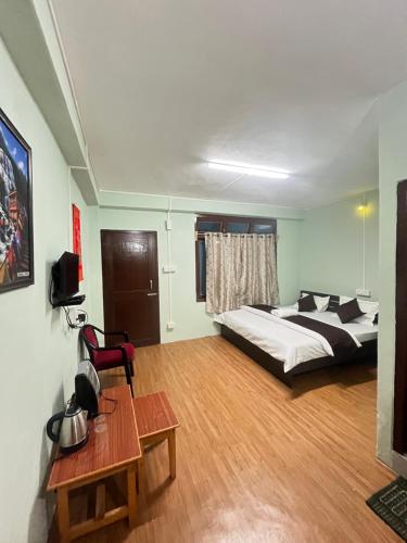 ein Schlafzimmer mit einem Bett, einem Tisch und einem Stuhl in der Unterkunft Hotel Tashi Tseleng in Tawang