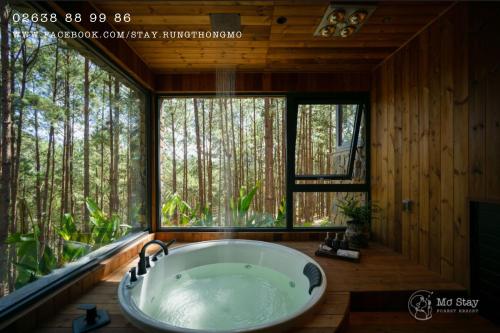 a bath tub in a room with a large window at Mơ Stay - Forest Resort in Da Lat