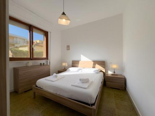 une chambre blanche avec un grand lit et une fenêtre dans l'établissement Casa Grecale - Delizioso Appartamento A Soli 300 m Dal Mare Con Giardino Privato E Posto Auto Privato, à Castiglione della Pescaia