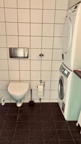 a bathroom with a toilet and a washing machine at Seaview and swimming in Hellerup