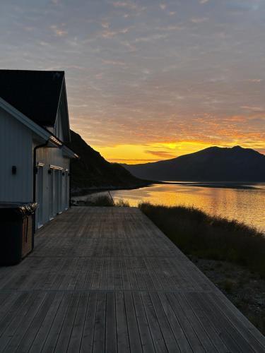 ein hölzerner Steg neben einem See bei Sonnenuntergang in der Unterkunft Arctic Fjord House - Fjord View, Sauna, Hot Tub in Karlsøy