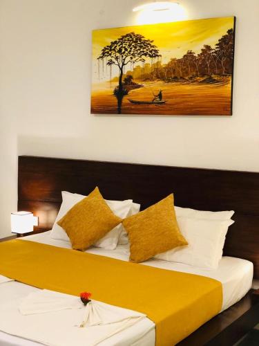 a bedroom with a large bed with yellow and white pillows at Paradise Garden Beruwala in Beruwala