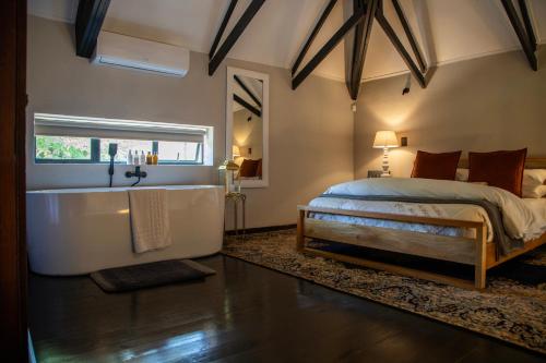 ein Schlafzimmer mit großem Bett und Badewanne in der Unterkunft Tarry-Stone Cottages in Dullstroom