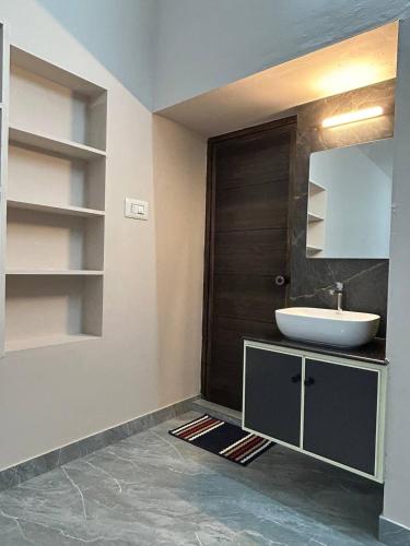 Un baño con lavabo y puerta de madera. en Cosy Stays, 2 Adjacent Apartments in Irinjalakuda, en Irinjālakuda