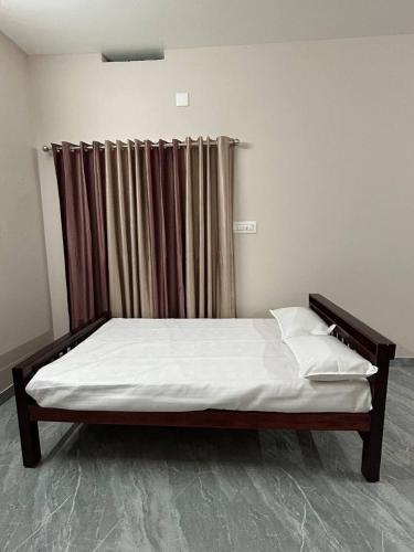 1 cama en una habitación con cortina en Cosy Stays, 2 Adjacent Apartments in Irinjalakuda, en Irinjālakuda