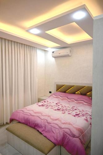 a bedroom with a bed with a pink blanket at Sky Villa in Amman