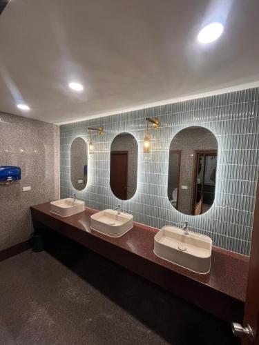 a bathroom with three sinks and three mirrors at Hatyai Merridian Hotel in Hat Yai