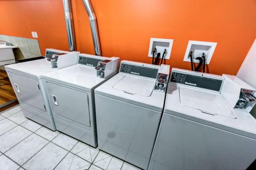 two washing machines in a room with an orange wall at Motel 6-Innisfail, AB in Innisfail