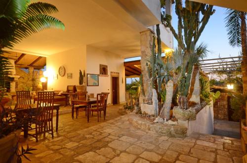 a dining room with tables and chairs and palm trees at Felline In Bed&Breakfast Dimora di Charme el Salento in Felline