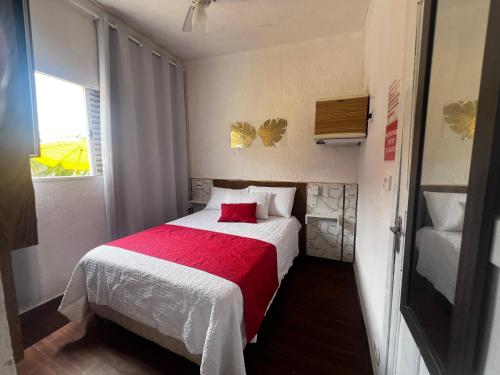 een kleine slaapkamer met een bed met een rode deken bij Recanto Guaraú 2 in Peruíbe