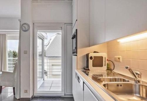 a kitchen with a sink and a microwave at Appartemment familial à Westende in Westende-Bad