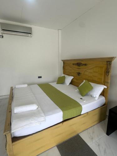 Schlafzimmer mit einem großen Bett mit weißer und grüner Bettwäsche in der Unterkunft OrientalResort Kekirawa in Kekirawa