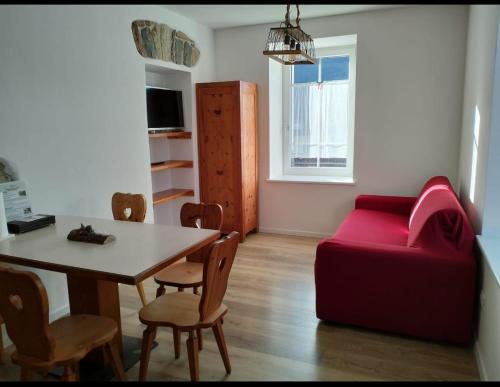 a living room with a table and a red couch at Appartamento a Tesero in Tesero