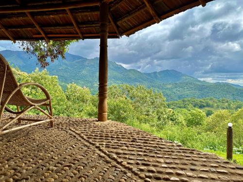 a bench sitting on a porch with a view of mountains at Pepper Hills Hostel & Cottages in Ella