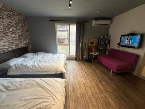 a bedroom with a bed and a couch and a tv at 輕鬆玩民宿 in Luodong