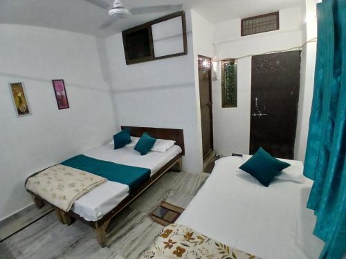 2 Einzelbetten in einem Zimmer mit blauen Vorhängen in der Unterkunft Kashvi Homestay in Varanasi
