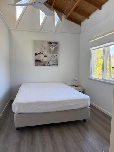 a white bedroom with a bed and a skylight at Beach House Getaway 1 in Smiths Beach